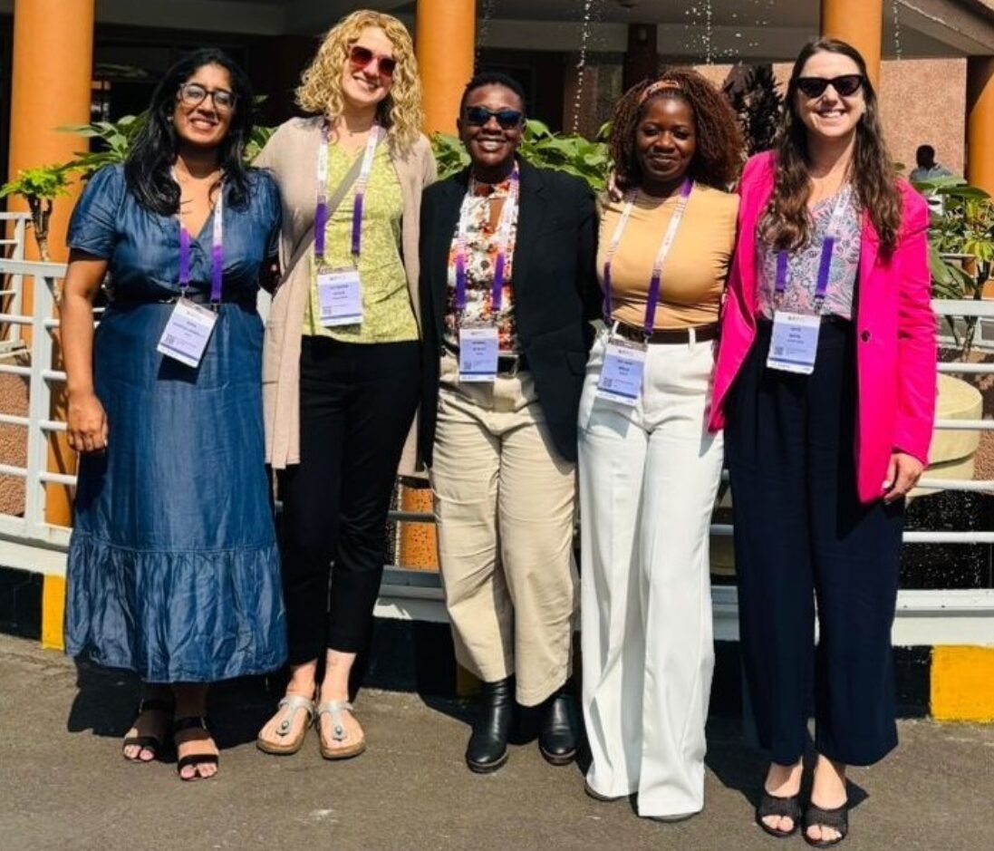 Five members of the Access Bridge team standing together outdoors wearing AIDS 2026 conference badges
